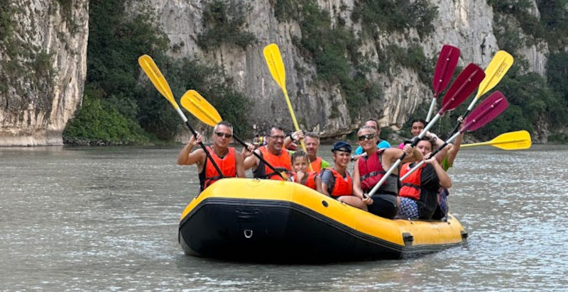 Gruppo di persone praticando rafting lungo il fiume Adige nella Val d'Adige