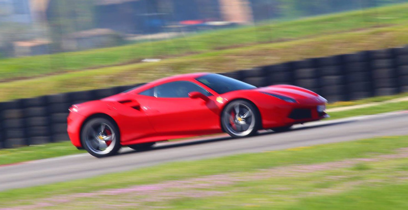 Esperienza di guida al volante della Ferrari 488 GTB rossa lungo i cordoli della pista di Arese