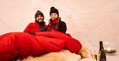 Coppia che brinda con champagne nell'igloo romantico