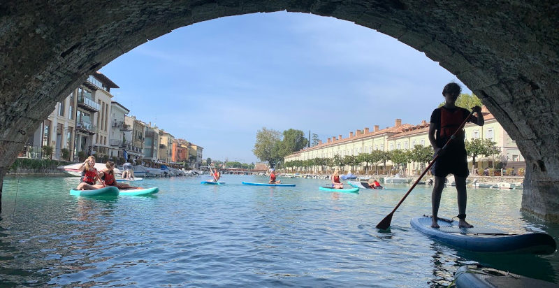 Persona in piedi su una tavola da paddle esplora i canali di Peschiera