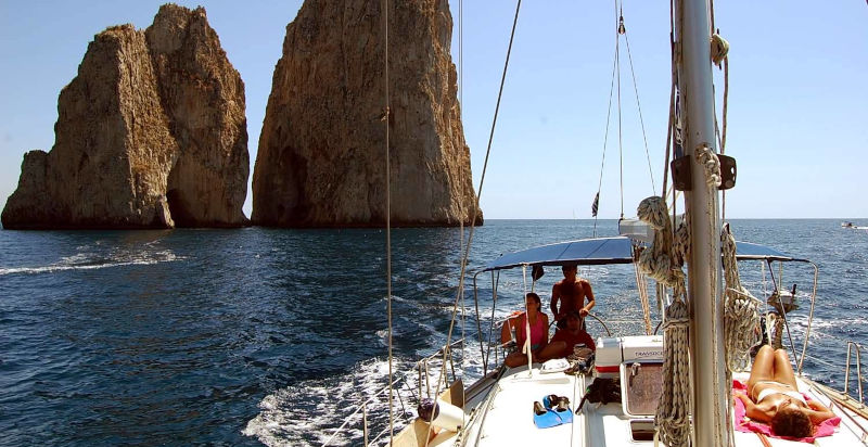 Barca a vela che costeggia i suggestivi faraglioni cilentani
